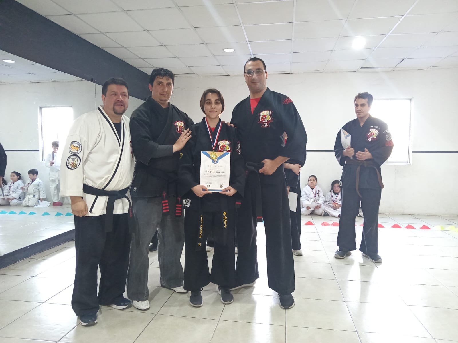Alumna recibiendo su certificado de grado acompañada por cuatro instructores